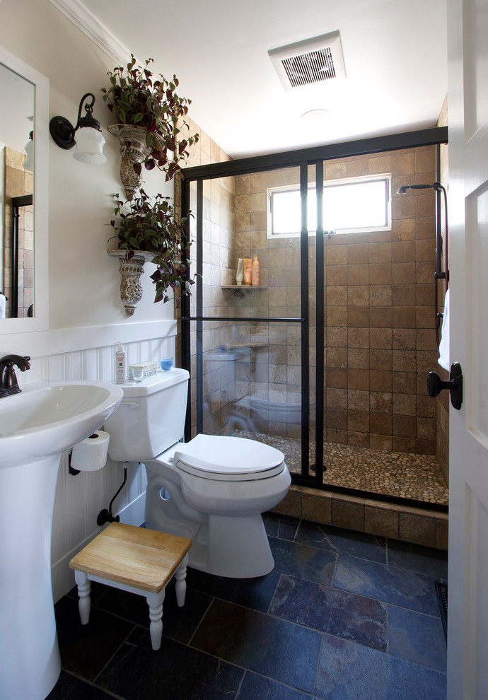 Inspiration for a small traditional 3/4 bathroom in Seattle with a pedestal sink, an alcove shower, a two-piece toilet, brown tile, pebble tile, white walls and slate floors.