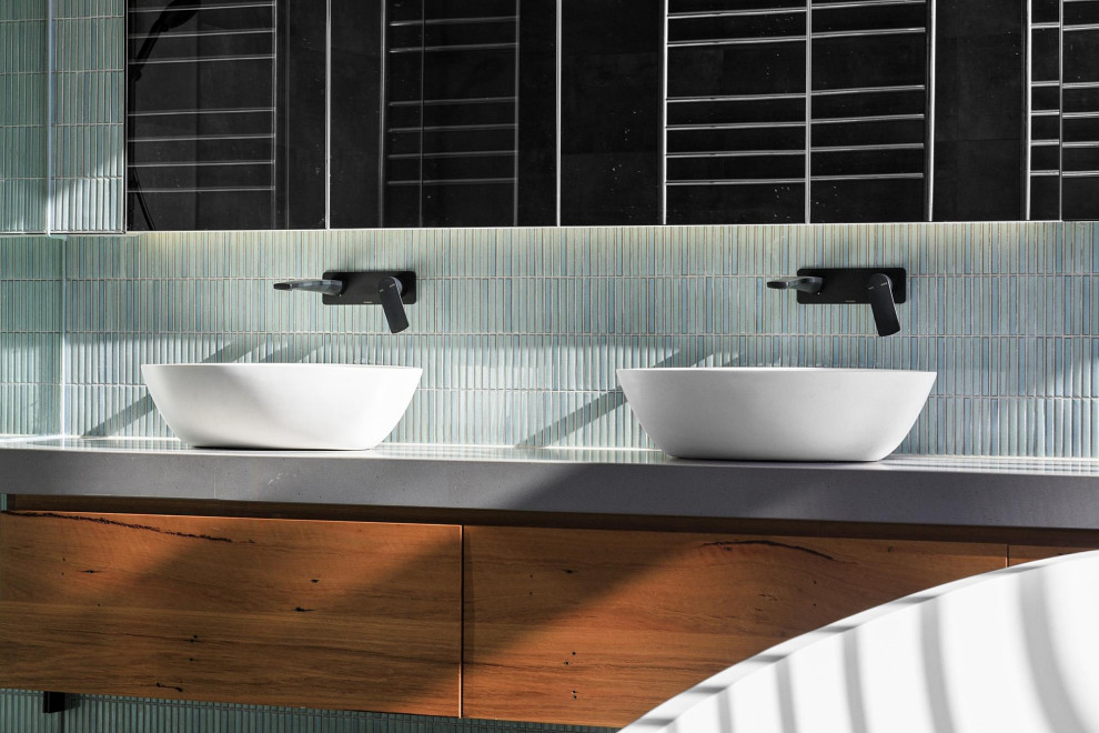 Inspiration for a large contemporary master bathroom in Geelong with flat-panel cabinets, medium wood cabinets, a freestanding tub, green tile, mosaic tile, a vessel sink, solid surface benchtops, grey benchtops, a double vanity and a floating vanity.