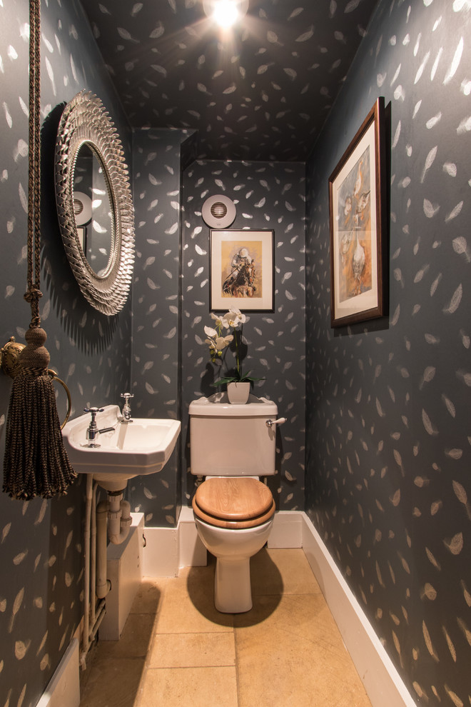 Traditional powder room in London with a two-piece toilet, black walls, a wall-mount sink and beige floor.