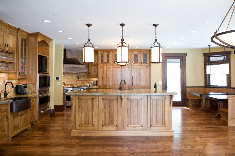 Inspiration for a large country u-shaped eat-in kitchen in Salt Lake City with an undermount sink, recessed-panel cabinets, medium wood cabinets, granite benchtops, multi-coloured splashback, stone tile splashback, stainless steel appliances, medium hardwood floors and multiple islands.