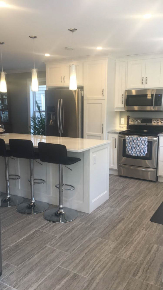 Eat-in kitchen - mid-sized transitional u-shaped porcelain tile and gray floor eat-in kitchen idea with recessed-panel cabinets, white cabinets, quartz countertops, an island, white countertops, stainless steel appliances and an undermount sink