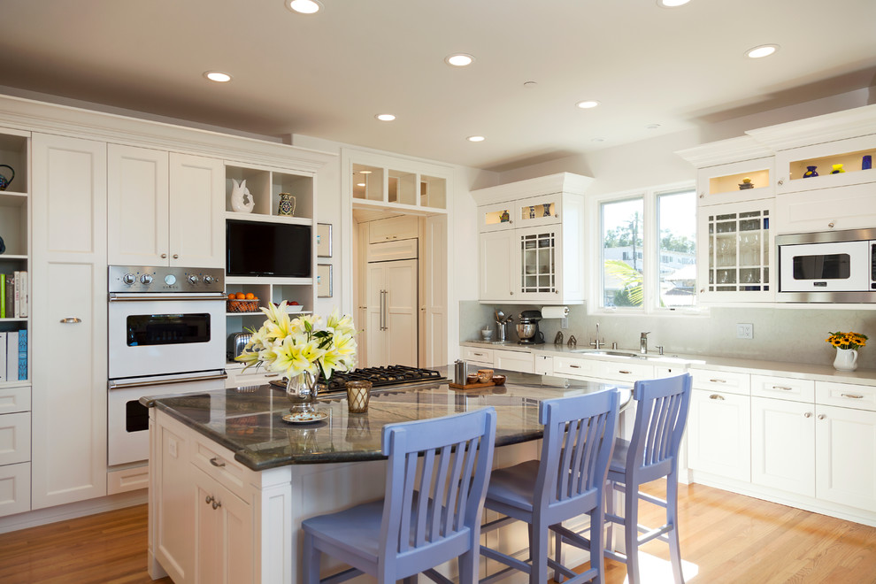 Large transitional light wood floor eat-in kitchen photo in Los Angeles with an undermount sink, recessed-panel cabinets, white cabinets, quartzite countertops, gray backsplash, stone slab backsplash, paneled appliances and an island
