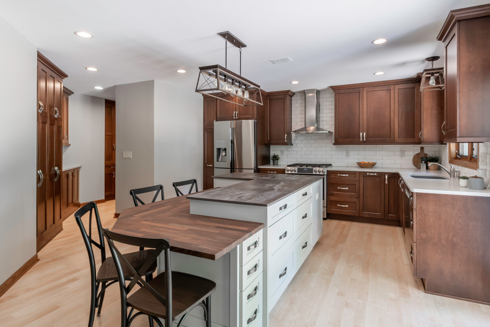 Enclosed kitchen - large transitional l-shaped light wood floor and brown floor enclosed kitchen idea in Milwaukee with an undermount sink, shaker cabinets, medium tone wood cabinets, wood countertops, white backsplash, subway tile backsplash, stainless steel appliances, an island and brown countertops