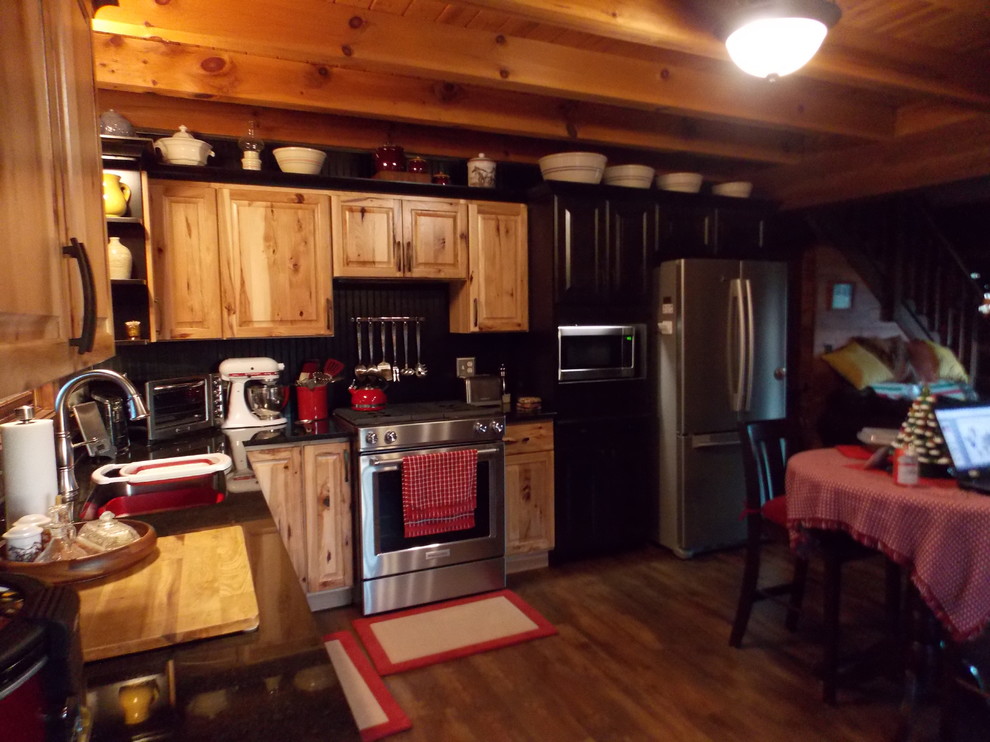 Small mountain style l-shaped vinyl floor and brown floor open concept kitchen photo in Indianapolis with an undermount sink, raised-panel cabinets, granite countertops, black backsplash, wood backsplash, stainless steel appliances and black countertops