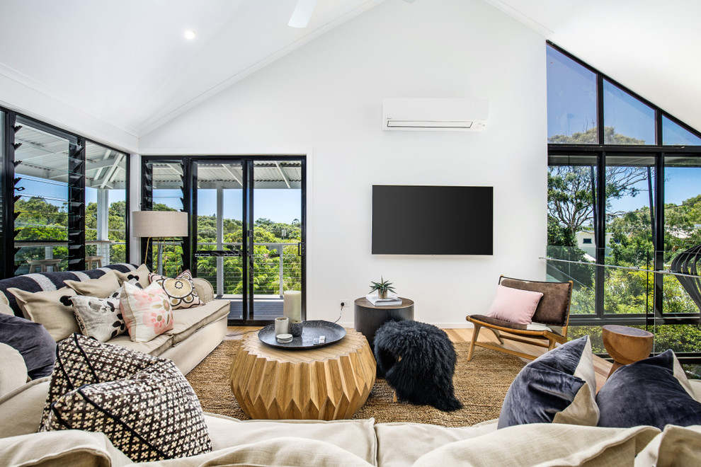 Large beach style open concept living room in Sunshine Coast with white walls, light hardwood floors, a wall-mounted tv and multi-coloured floor.