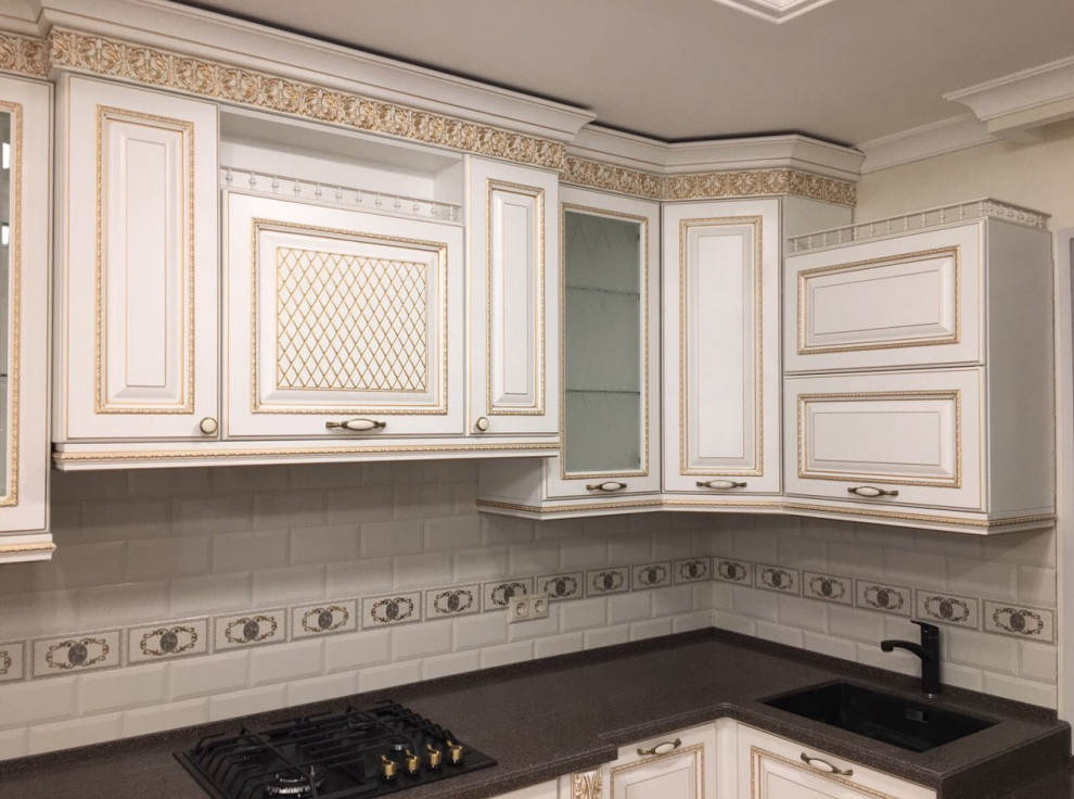 Large elegant l-shaped ceramic tile, beige floor and tray ceiling eat-in kitchen photo in Other with an undermount sink, raised-panel cabinets, beige cabinets, solid surface countertops, multicolored backsplash, porcelain backsplash, black appliances, an island and brown countertops
