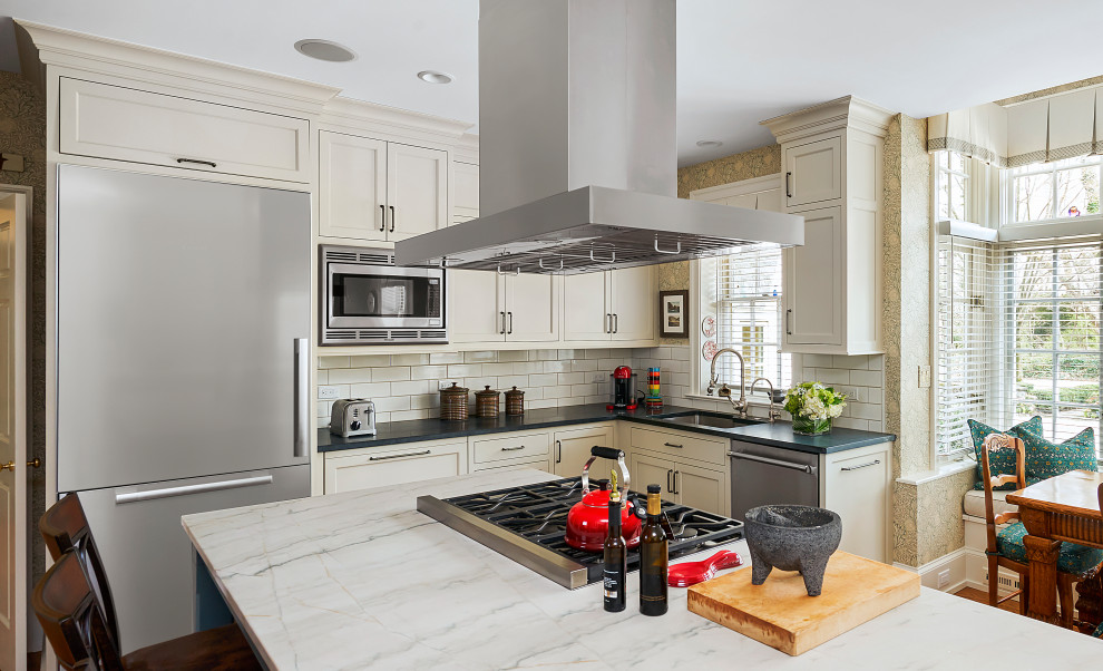 Inspiration for a large transitional l-shaped medium tone wood floor and brown floor enclosed kitchen remodel in Philadelphia with a double-bowl sink, recessed-panel cabinets, green cabinets, soapstone countertops, beige backsplash, ceramic backsplash, stainless steel appliances, an island and beige countertops