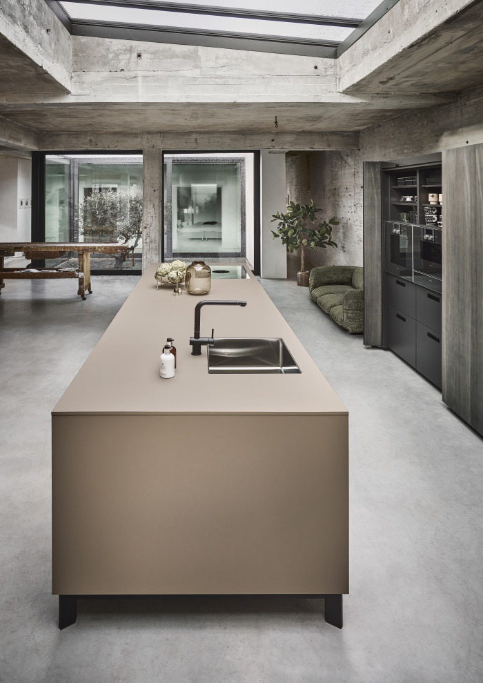 Scandinavian galley open plan kitchen in Nuremberg with flat-panel cabinets, beige cabinets, black appliances, with island and beige benchtop.