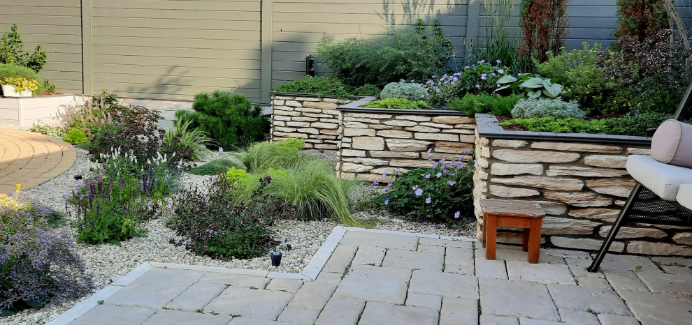 Foto di un piccolo giardino xeriscape tradizionale esposto in pieno sole dietro casa in estate con sassi e rocce, pavimentazioni in cemento e recinzione in legno