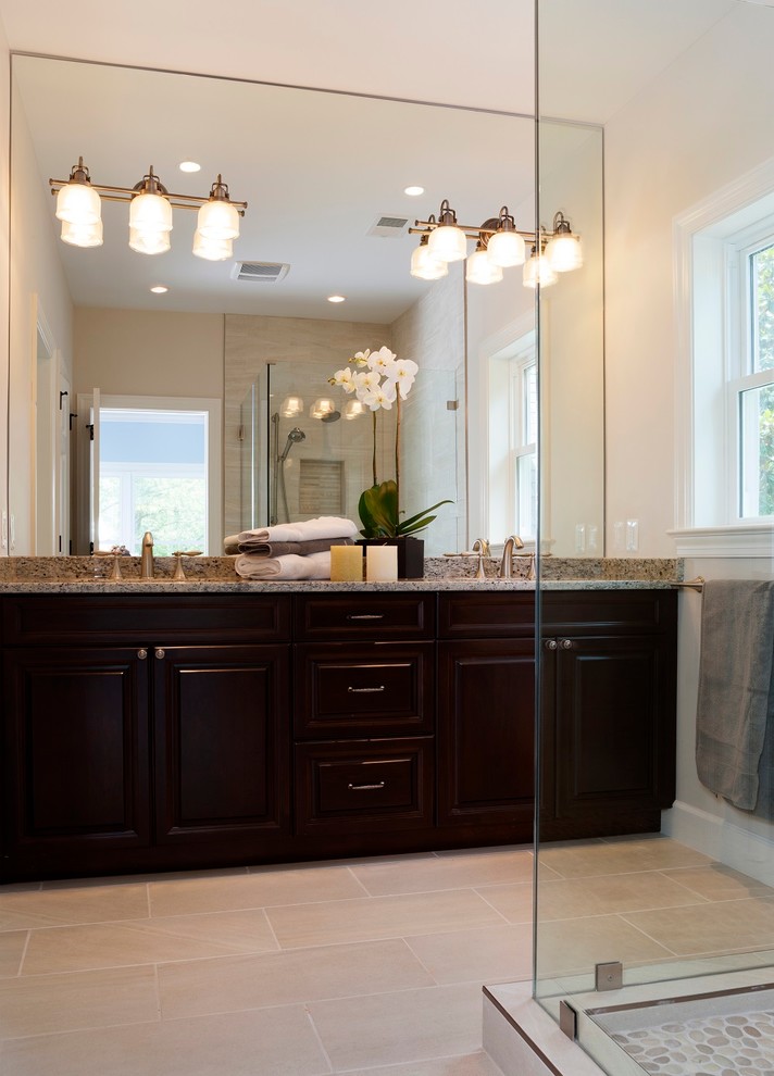 This is an example of a mid-sized traditional 3/4 bathroom in DC Metro with a corner shower, raised-panel cabinets, black cabinets, a one-piece toilet, beige tile, beige walls, ceramic floors, an undermount sink, granite benchtops, beige floor, a hinged shower door and ceramic tile.