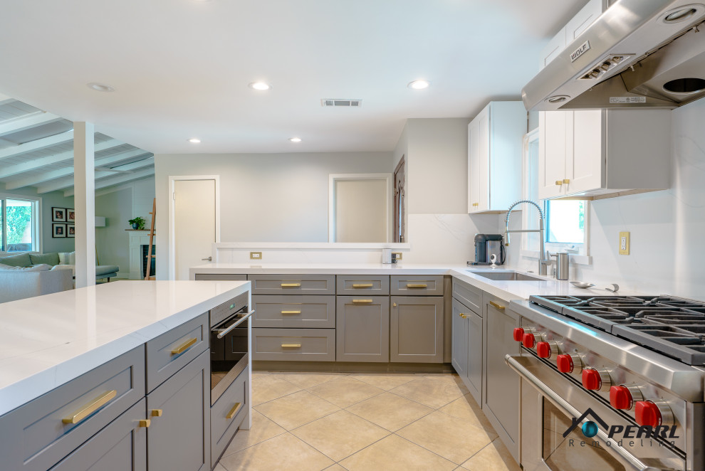 This is an example of a mid-sized modern l-shaped eat-in kitchen in Los Angeles with a drop-in sink, shaker cabinets, grey cabinets, marble benchtops, white splashback, marble splashback, stainless steel appliances, ceramic floors, a peninsula, beige floor, white benchtop and timber.