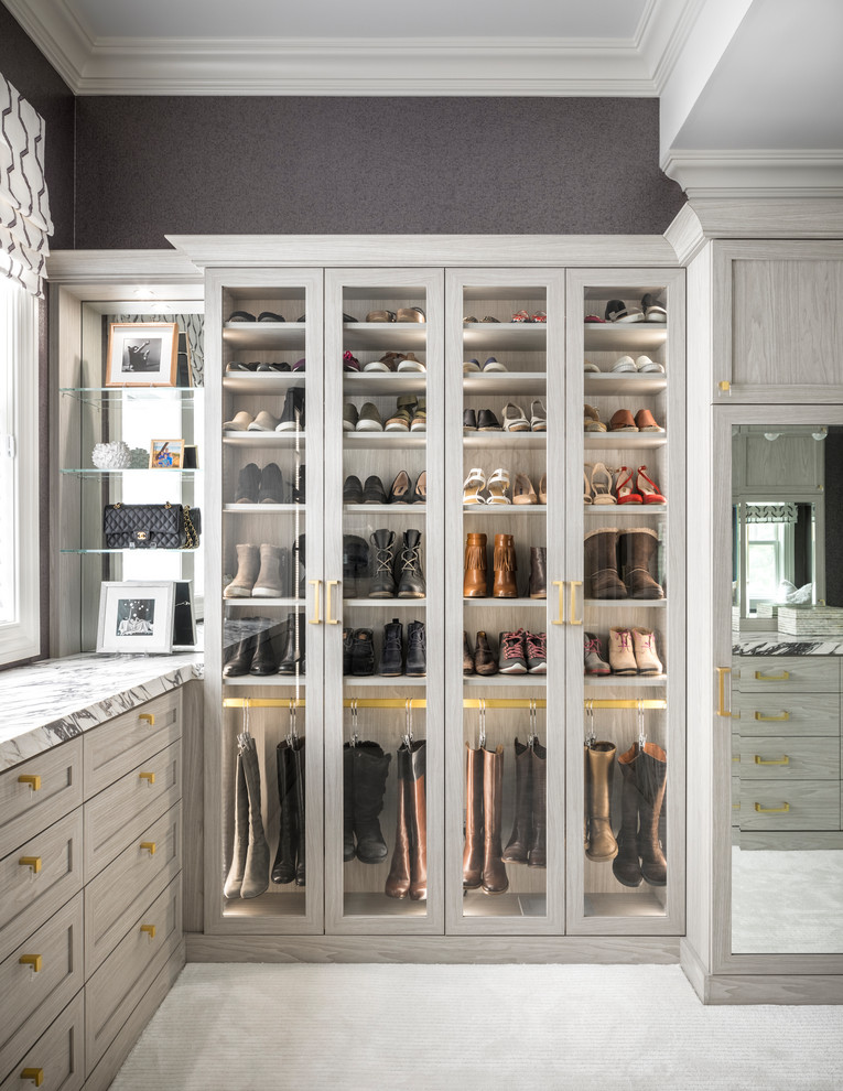 Photo of a modern women's dressing room in New York with recessed-panel cabinets, light wood cabinets, carpet and grey floor.