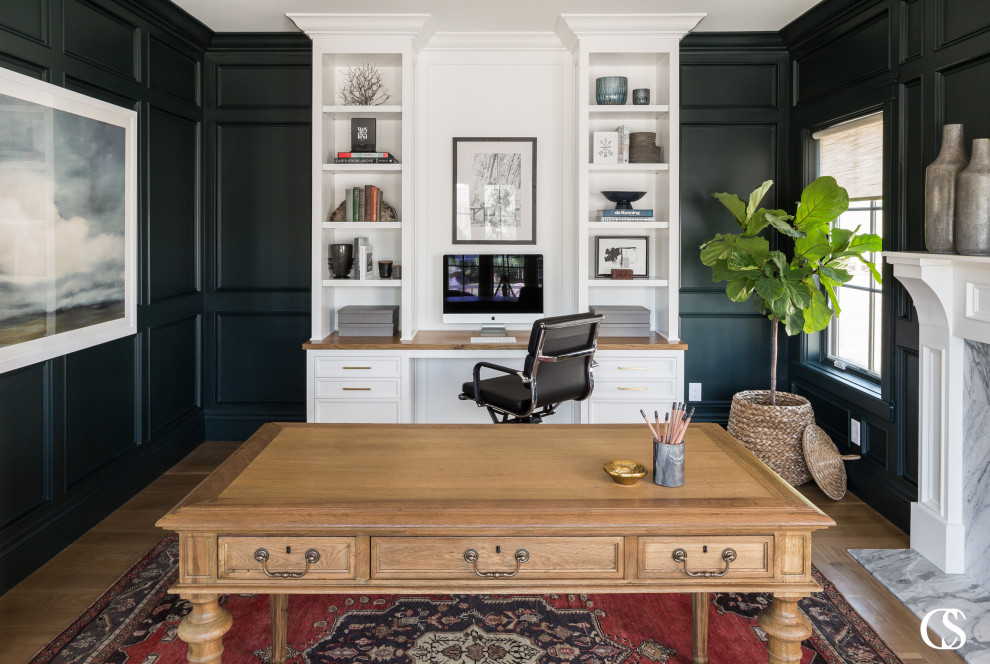 Photo of a classic home office in Salt Lake City with green walls, medium hardwood flooring, a standard fireplace, a stone fireplace surround, a freestanding desk and panelled walls.