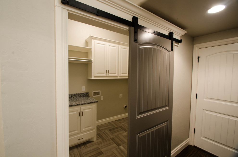 Mid-sized traditional galley dedicated laundry room in Oklahoma City with raised-panel cabinets, white cabinets, granite benchtops, beige walls, ceramic floors and a side-by-side washer and dryer.