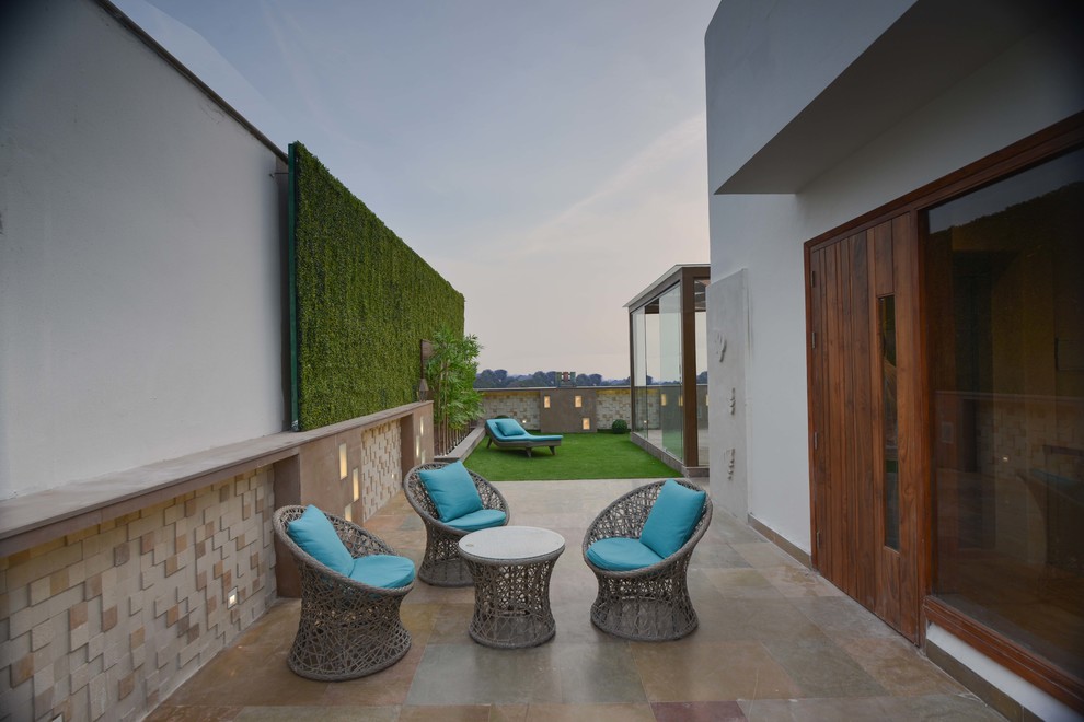 Inspiration for a mid-sized contemporary rooftop partial sun garden in Delhi with concrete pavers.