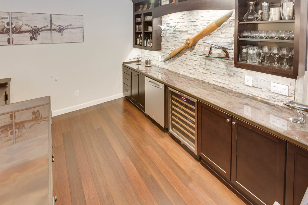 This is an example of a large modern u-shaped wet bar in DC Metro with a drop-in sink, recessed-panel cabinets, copper benchtops, stone tile splashback and medium hardwood floors.