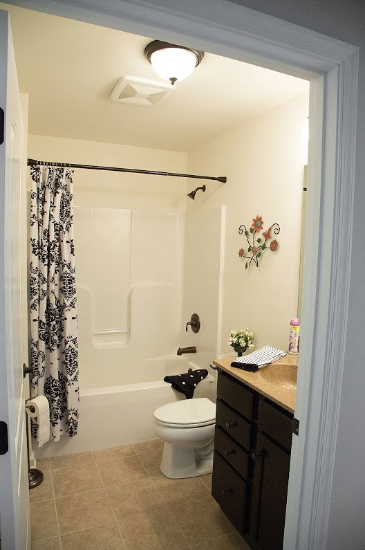 This is an example of a mid-sized traditional master bathroom in Philadelphia with flat-panel cabinets, dark wood cabinets, an alcove tub, a shower/bathtub combo, a two-piece toilet, white walls, ceramic floors, an integrated sink, laminate benchtops and a shower curtain.