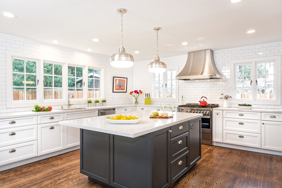 Inspiration for a traditional l-shaped kitchen in San Francisco with an undermount sink, raised-panel cabinets, white cabinets, white splashback, stone tile splashback, stainless steel appliances, medium hardwood floors and with island.