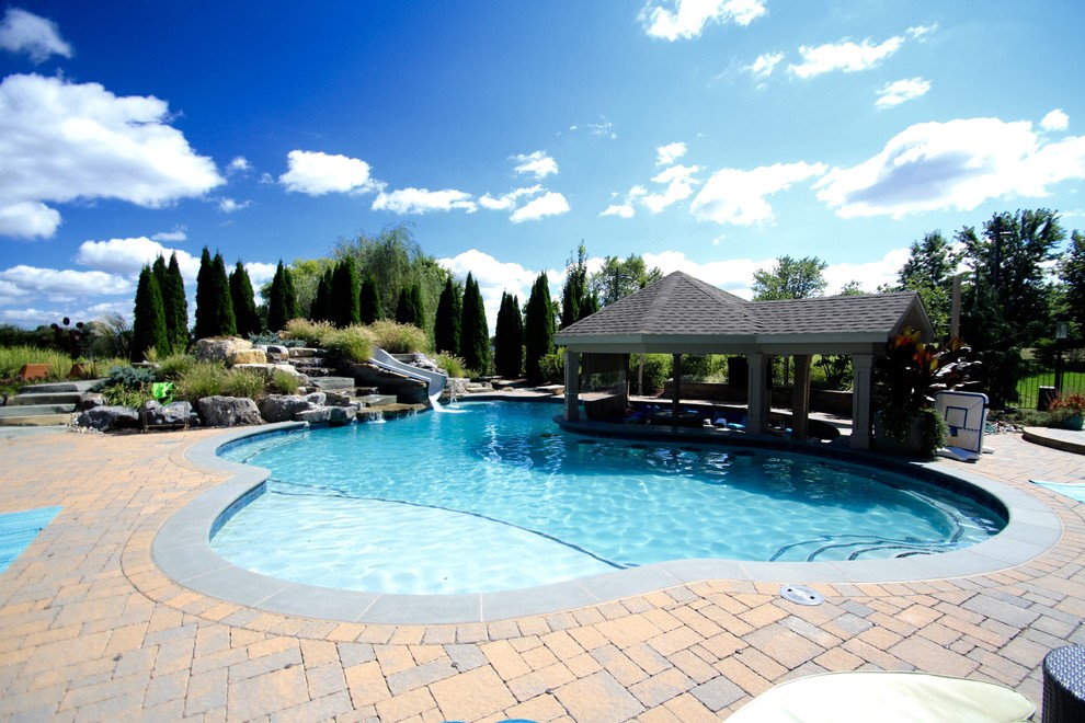 Large contemporary backyard custom-shaped pool in Philadelphia with a water slide and concrete pavers.