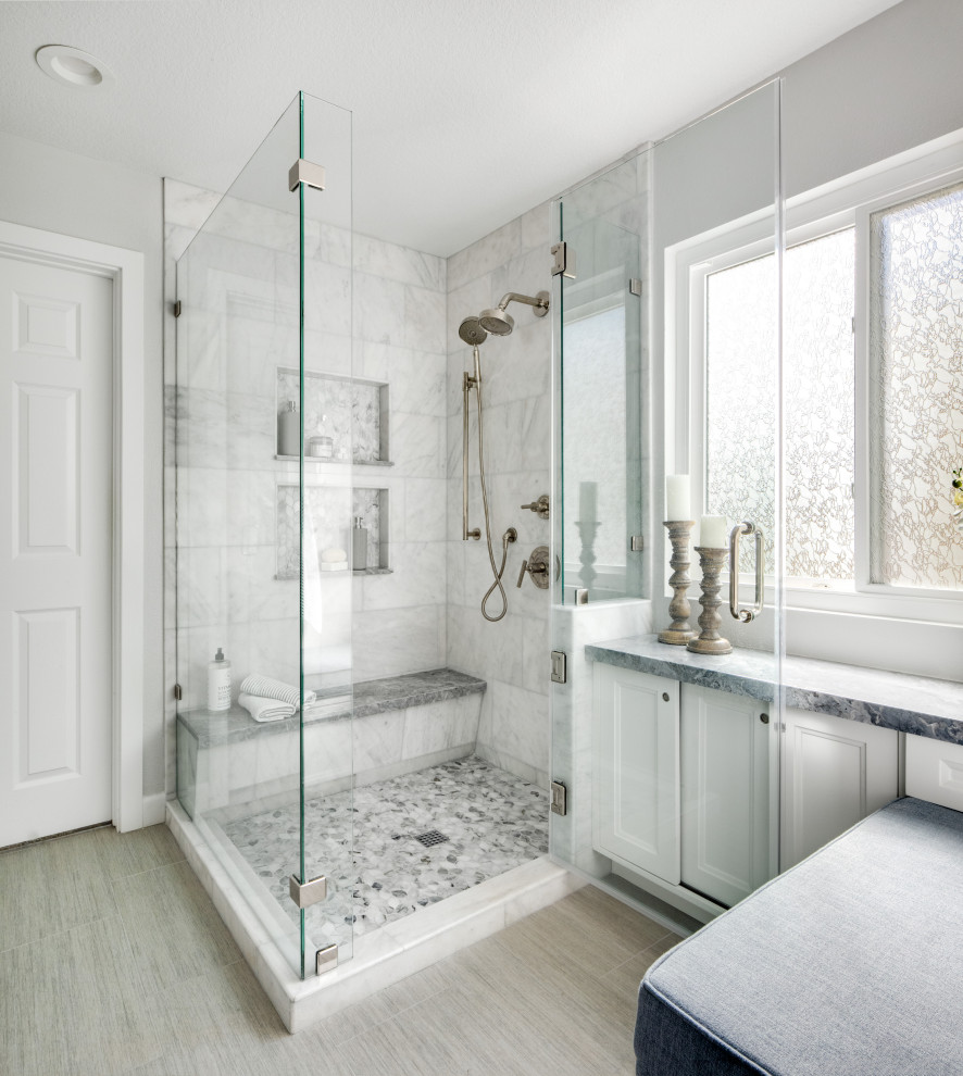 Идея дизайна: главная ванная комната среднего размера в стиле неоклассика (современная классика) с фасадами в стиле шейкер, белыми фасадами, угловым душем, унитазом-моноблоком, белой плиткой, мраморной плиткой, белыми стенами, полом из керамогранита, врезной раковиной, мраморной столешницей, серым полом, душем с распашными дверями, синей столешницей, сиденьем для душа, тумбой под две раковины и встроенной тумбой