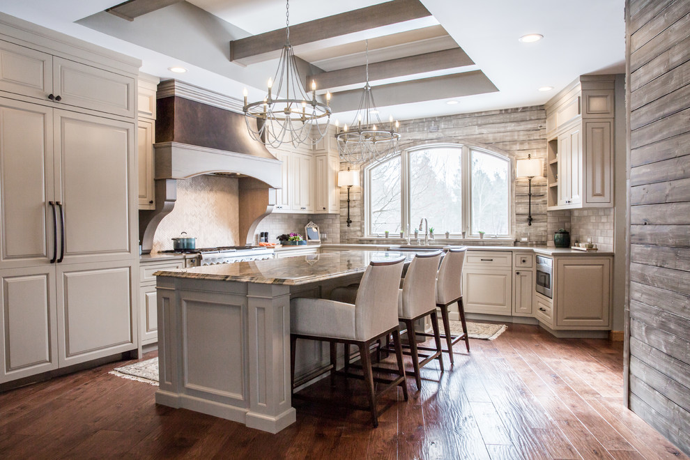 Inspiration for a traditional u-shaped kitchen in Cleveland with raised-panel cabinets, beige cabinets, grey splashback, panelled appliances, medium hardwood floors, with island and grey benchtop.