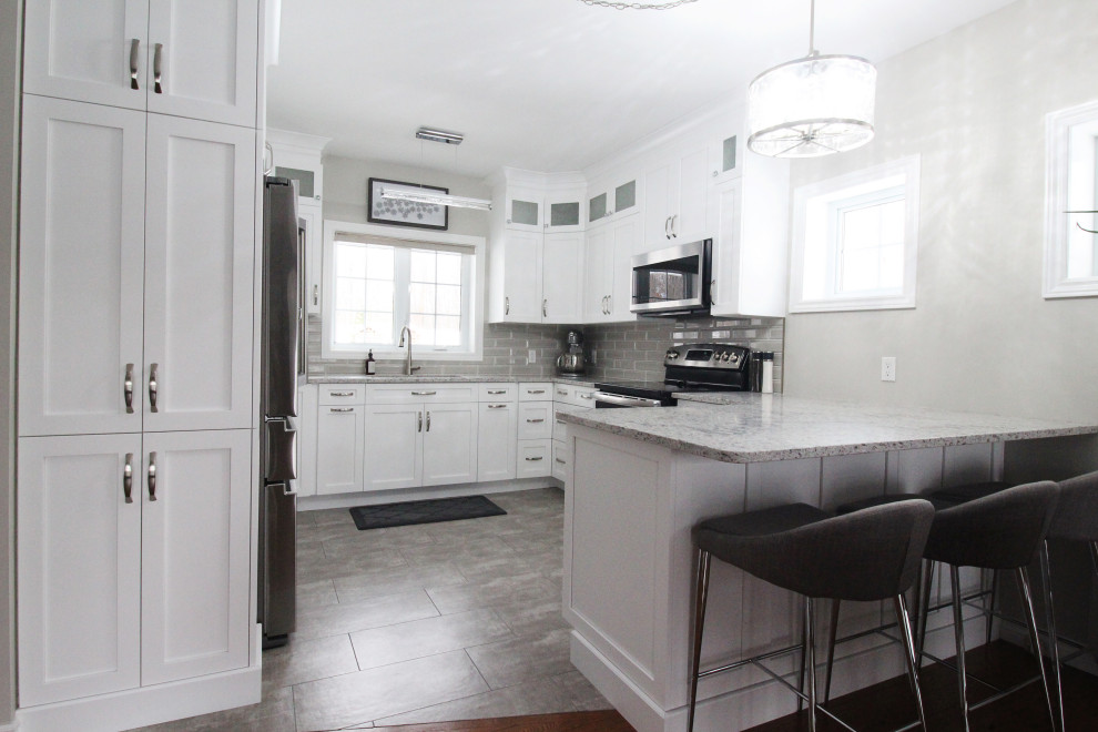 Kitchen - u-shaped kitchen idea with shaker cabinets, white cabinets, quartzite countertops, gray backsplash, subway tile backsplash, a peninsula and gray countertops