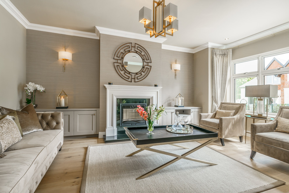 Design ideas for a large transitional enclosed living room in Dublin with beige walls, light hardwood floors, a standard fireplace, a plaster fireplace surround and beige floor.