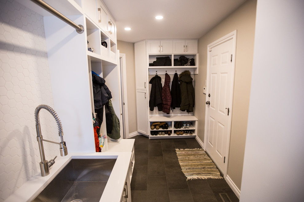 Photo of a mid-sized contemporary galley utility room in Edmonton with an undermount sink, recessed-panel cabinets, white cabinets, quartz benchtops, beige walls, porcelain floors and a stacked washer and dryer.