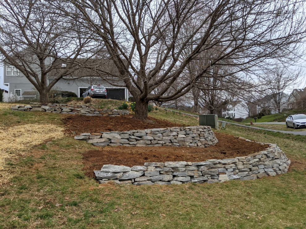 This is an example of a large front yard garden in Other with a retaining wall.