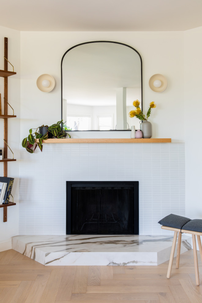 Inspiration for a small scandi open plan living room in San Francisco with white walls, light hardwood flooring, a corner fireplace, a tiled fireplace surround, no tv and brown floors.