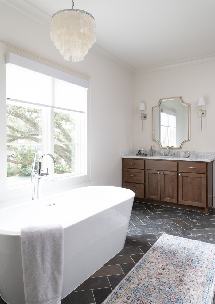 Inspiration for a large transitional master bathroom in Houston with shaker cabinets, medium wood cabinets, a freestanding tub, an undermount sink, marble benchtops, black floor and white benchtops.