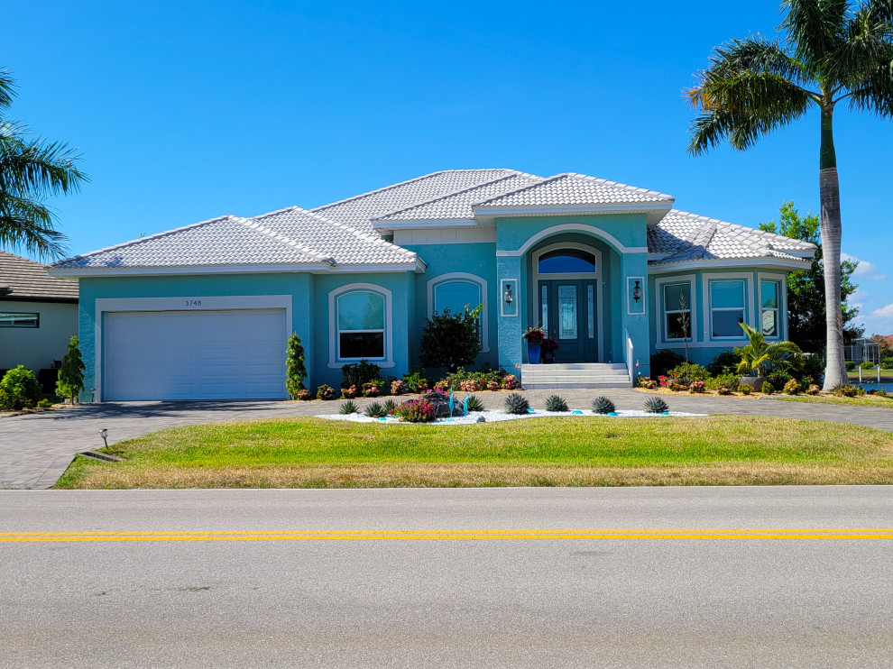 This is an example of a large and blue classic bungalow render and front detached house in Orlando with a hip roof, a tiled roof and a white roof.