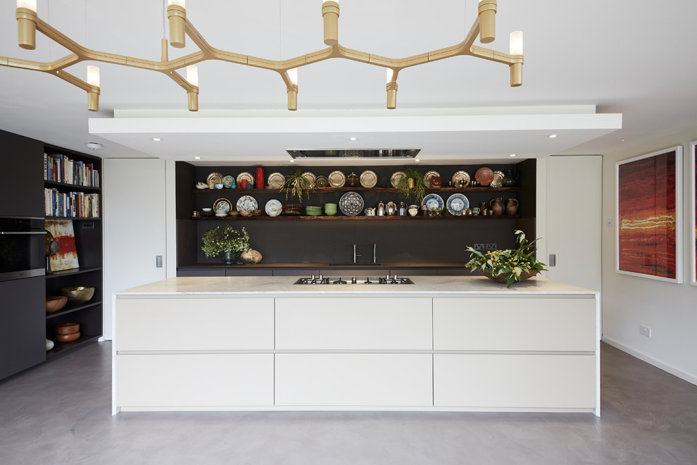 Large eclectic open plan kitchen in London with a single-bowl sink, flat-panel cabinets, beige cabinets, quartzite benchtops, panelled appliances, concrete floors, with island, grey floor and beige benchtop.
