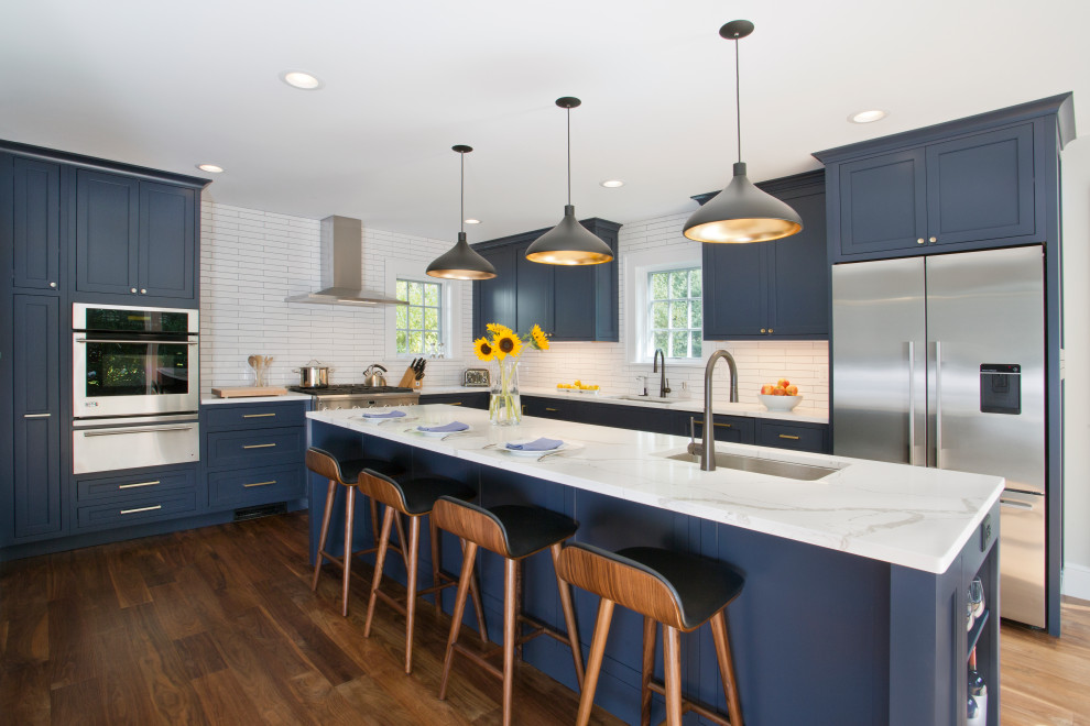 Inspiration for a mid-sized transitional l-shaped kitchen in New York with a single-bowl sink, flat-panel cabinets, blue cabinets, quartz benchtops, white splashback, ceramic splashback, stainless steel appliances, medium hardwood floors, with island, brown floor and white benchtop.