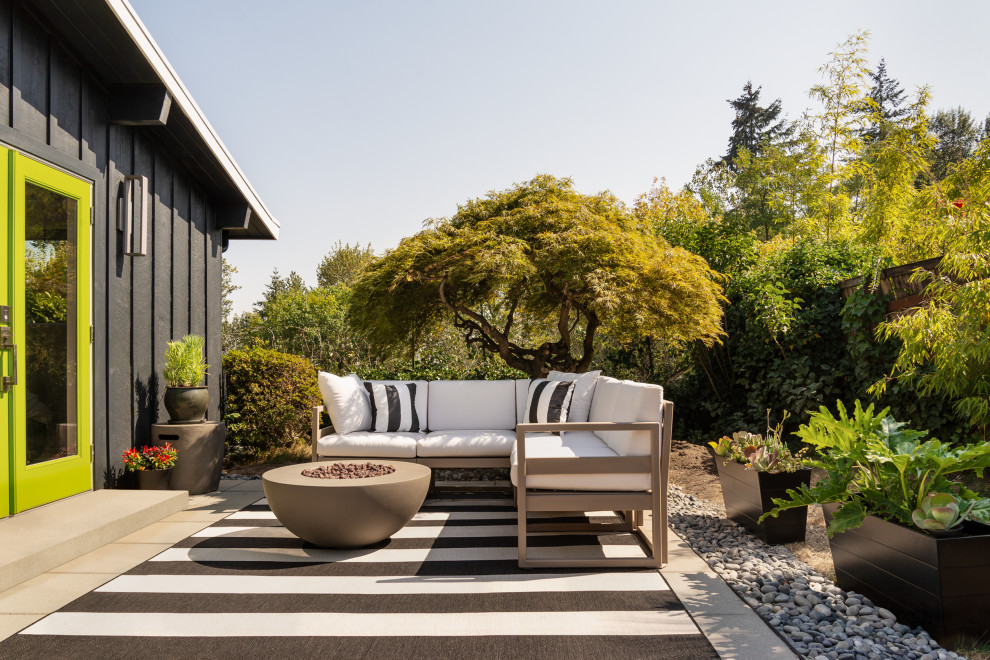 This is an example of a small midcentury backyard patio in Seattle with concrete pavers, no cover and a fire feature.