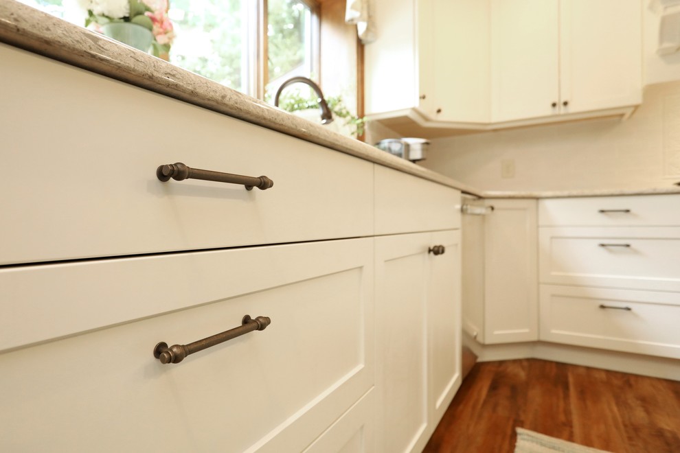 Kitchen - transitional vinyl floor and brown floor kitchen idea with an undermount sink, white cabinets, quartz countertops, white backsplash, subway tile backsplash, stainless steel appliances, an island and beige countertops