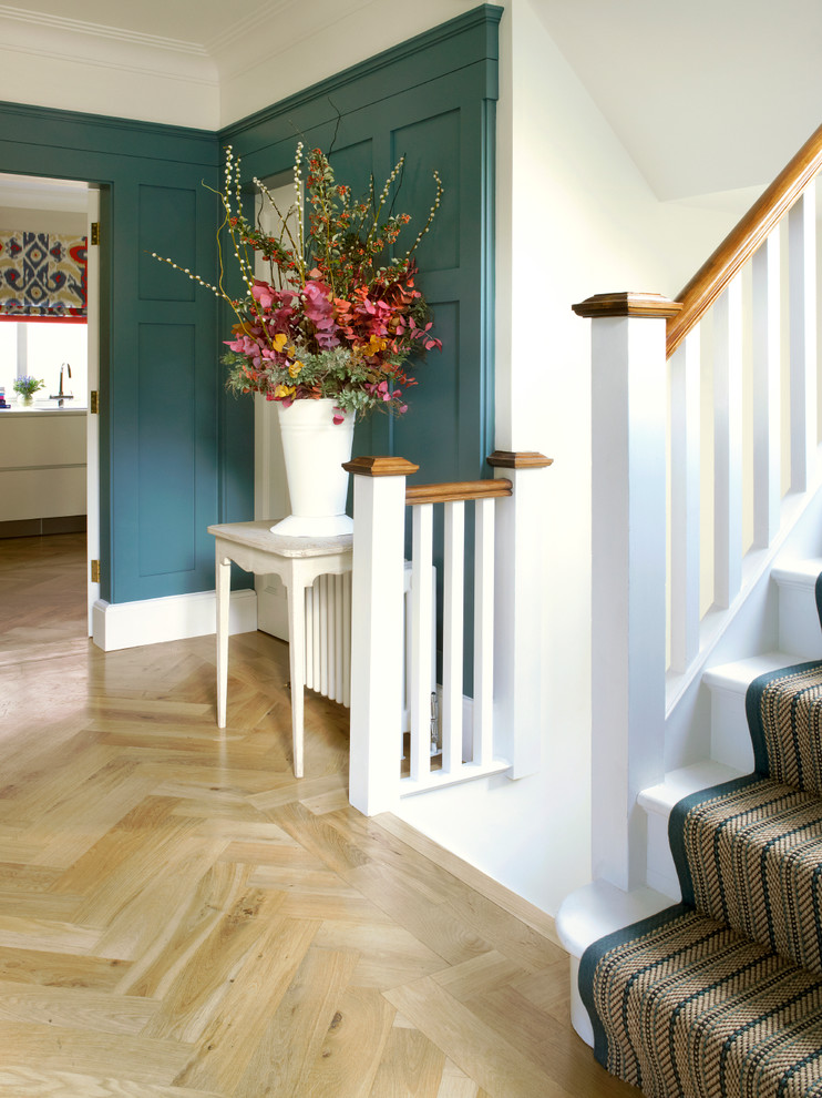 Mid-sized transitional hallway in London with blue walls and light hardwood floors.