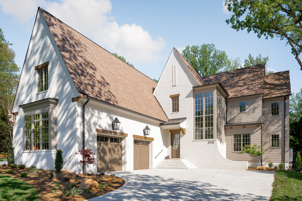 Cette image montre une grande façade de maison blanche design en brique à un étage avec un toit en shingle et un toit marron.