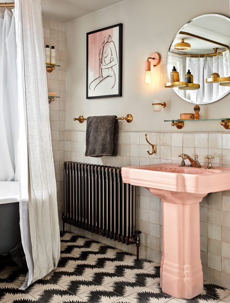 ロンドンにある低価格の中くらいなおしゃれなマスターバスルーム (置き型浴槽、シャワー付き浴槽	、ピンクのタイル、セラミックタイル、ペデスタルシンク、シャワーカーテン、洗面台1つ、ベージュの壁、磁器タイルの床) の写真