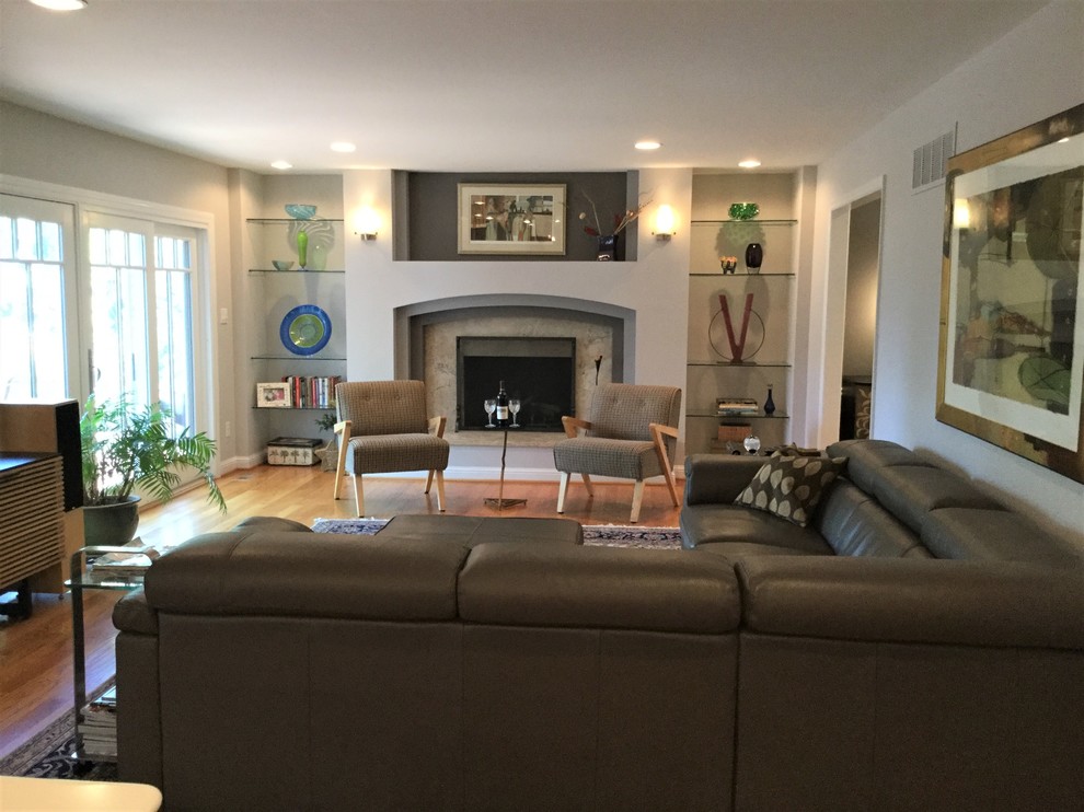 This is an example of a large contemporary open concept family room in St Louis with grey walls, light hardwood floors, a standard fireplace, a stone fireplace surround and a freestanding tv.