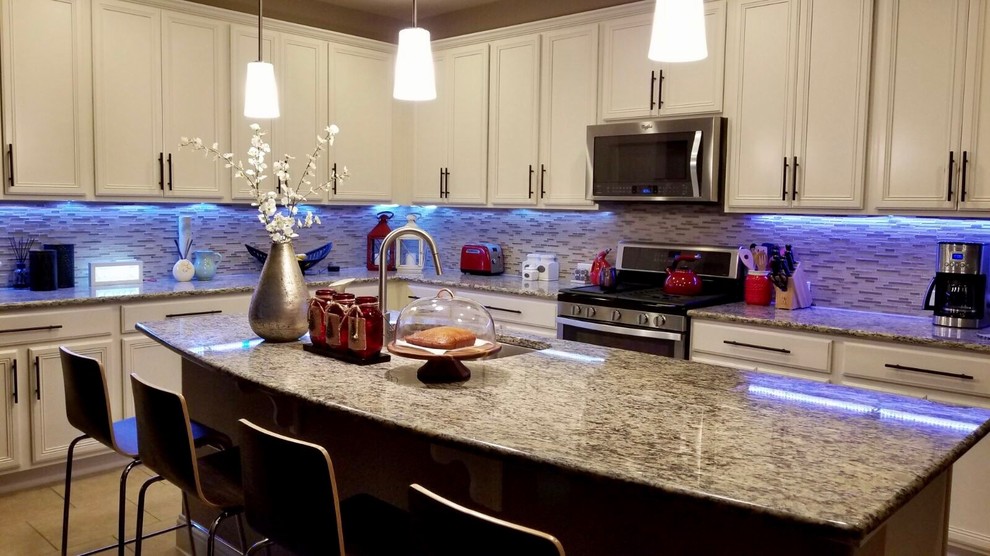Inspiration for a large transitional u-shaped ceramic tile eat-in kitchen remodel in Austin with a double-bowl sink, raised-panel cabinets, white cabinets, granite countertops, multicolored backsplash, matchstick tile backsplash, stainless steel appliances and an island