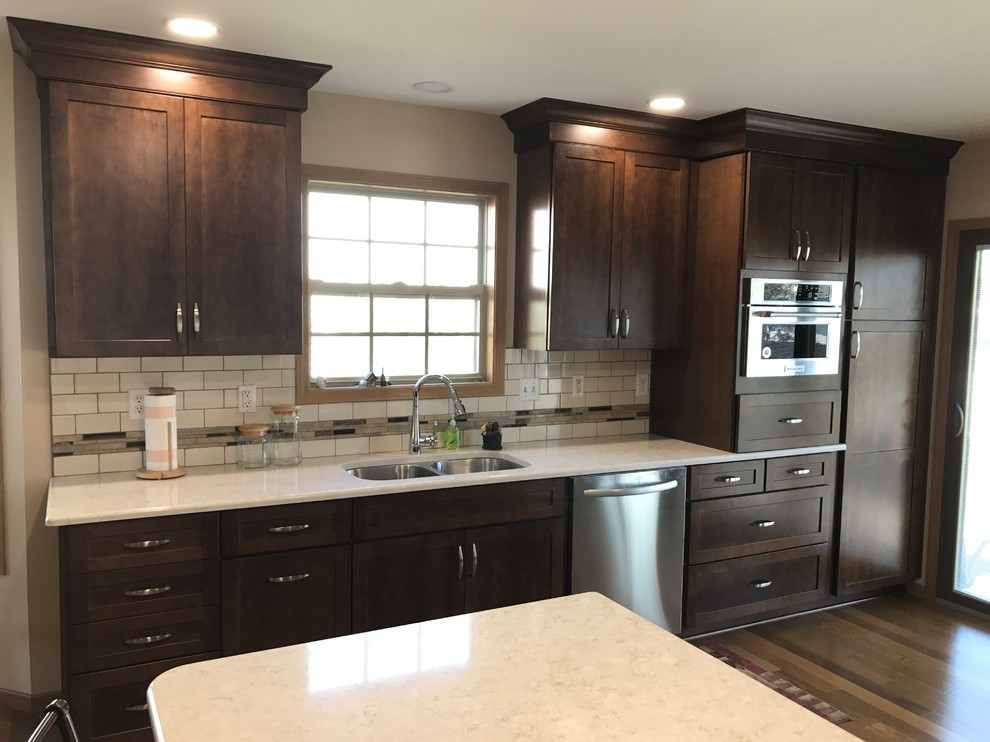 This is an example of a mid-sized traditional galley eat-in kitchen in Other with an undermount sink, shaker cabinets, medium wood cabinets, quartz benchtops, beige splashback, stainless steel appliances, medium hardwood floors, a peninsula and brown floor.