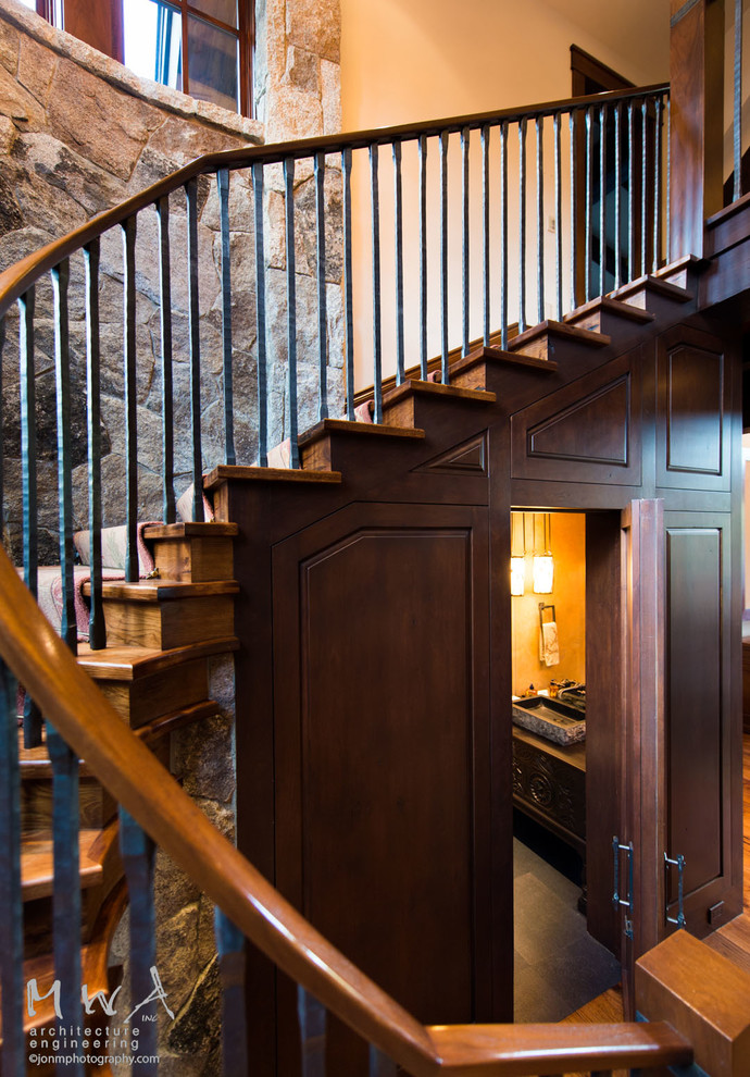 Large transitional wood curved staircase in Other with wood risers and metal railing.