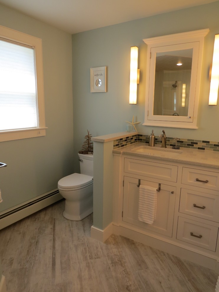Inspiration for a mid-sized beach style master bathroom in Portland Maine with an undermount sink, white cabinets, engineered quartz benchtops, a curbless shower, a two-piece toilet, multi-coloured tile, glass tile, blue walls, porcelain floors and shaker cabinets.