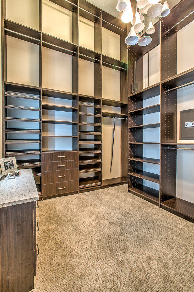This is an example of a large transitional gender-neutral walk-in wardrobe in Omaha with flat-panel cabinets, medium wood cabinets and carpet.