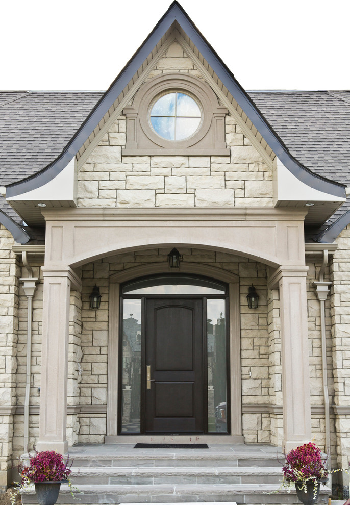 Photo of a large traditional one-storey beige exterior in Toronto with stone veneer and a gable roof.