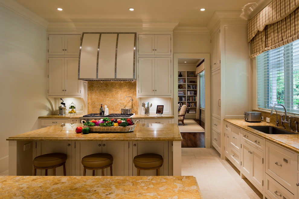 This is an example of a large traditional galley eat-in kitchen in Miami with an undermount sink, flat-panel cabinets, beige cabinets, granite benchtops, yellow splashback, granite splashback, stainless steel appliances, multiple islands, white floor, yellow benchtop and travertine floors.