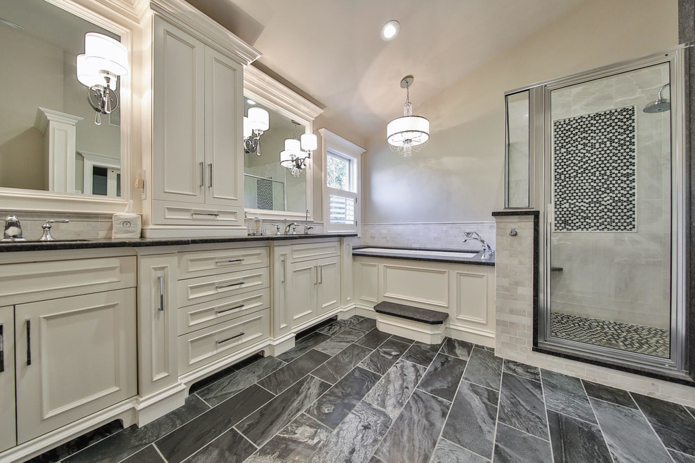 Corner shower - large transitional master gray tile and marble tile gray floor corner shower idea with beaded inset cabinets, white cabinets, an undermount tub, beige walls, an undermount sink, granite countertops, a hinged shower door and black countertops
