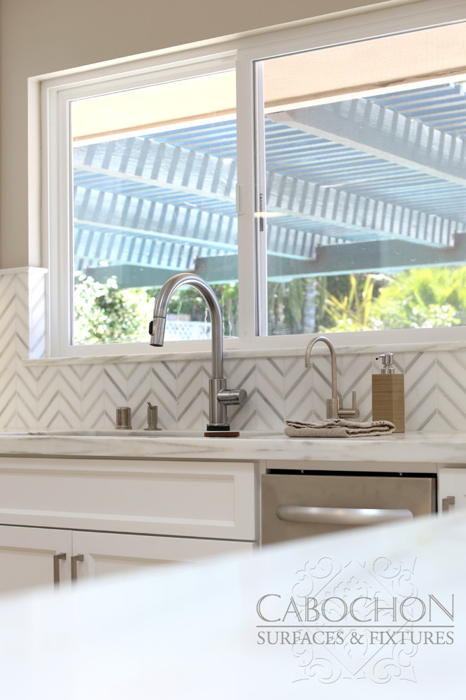 Inspiration for a mid-sized transitional l-shaped limestone floor open concept kitchen remodel in San Diego with an island, shaker cabinets, white cabinets, marble countertops, white backsplash, mosaic tile backsplash, stainless steel appliances, an undermount sink and beige walls