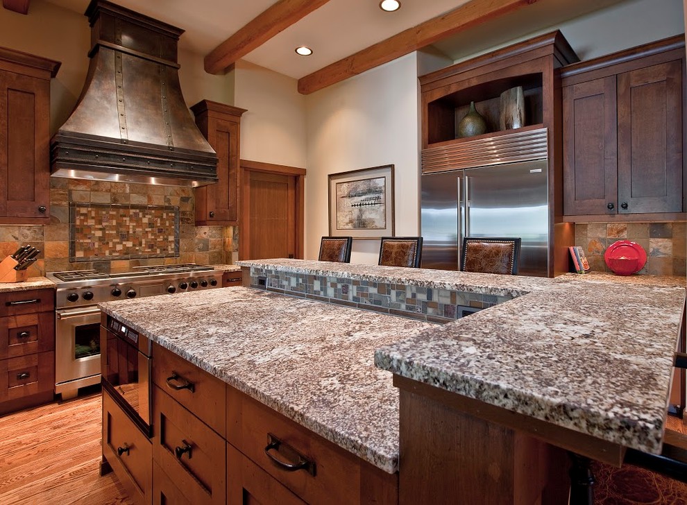 Inspiration for a large rustic l-shaped medium tone wood floor kitchen remodel in Seattle with granite countertops, multicolored backsplash, stainless steel appliances, an island, an undermount sink, shaker cabinets, dark wood cabinets and stone tile backsplash